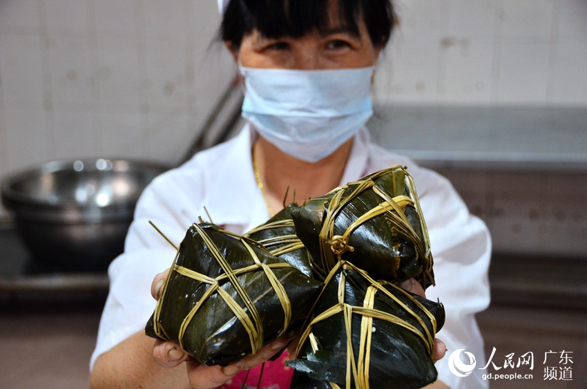 6月17日，广东肇庆市肥仔伟食品有限公司的生产车间内，一名工人为记者展示肇庆裹蒸粽。肇庆裹蒸粽誉满岭南，是用当地特有的冬叶、水草裹成的大大的粽子，所以称作裹蒸粽。与一般粽子用竹叶包制，呈四面三角形不同，裹蒸粽呈枕头状或是四角山包状。田伟 摄
