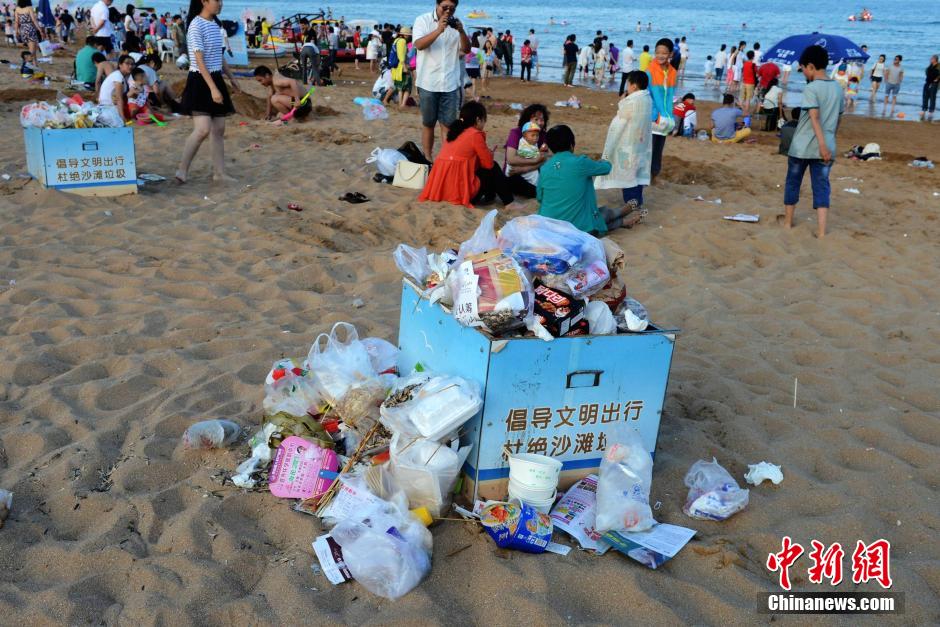 青岛海水浴场垃圾煞风景 游客垃圾中穿梭留影