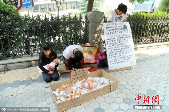 9月20日，中秋佳节临近，在河南省会郑州街头现感人一幕，两位年轻的兄弟跪在路边为救患重病父亲，售卖爱心人士捐赠的月饼，引得路人围观捐助。CFP视觉中国