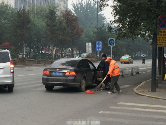 而此时，一位60多岁的环卫工人就站在这辆小轿车不远处，看见有人往路上扔垃圾，环卫工人先是站在一边，看到男子没有将垃圾扔进垃圾箱的意思，环卫工人默默地走上前去，将男子扔下车的垃圾扫进簸箕里。[!--empirenews.page--]