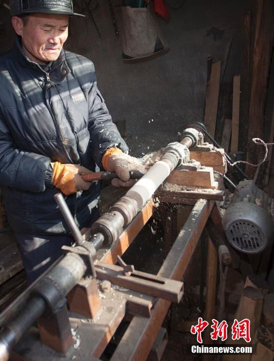 李景阳在自己的工作室中制作一个部件。