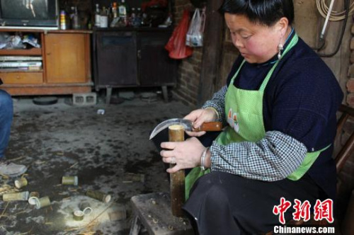 卡拉村，一位村妇正在劈竹子，为家中的鸟笼生意提供原材料。中新网记者 陈伊昕 摄