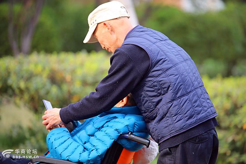都市现代气息小区里八旬老人轮椅上玩自拍